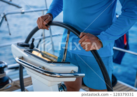 Man steering a sailing yacht using navigation display and control panel near Croatia. Precision, control and modern sailing lifestyle at sea. Man steering a sailing yacht using navigation display and control panel near Croatia. Precision, control and modern sailing lifestyle at sea. 128379331