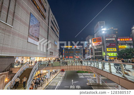 Night view of the west exit of Kita-Senju Station and the pedestrian deck with people passing by Night view of the west exit of Kita-Senju Station and the pedestrian deck with people passing by 128380537