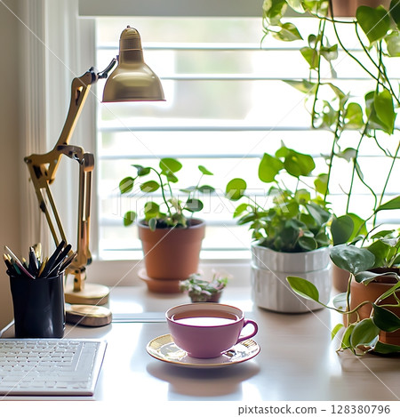 A desk with a lamp, a pink cup, and several potted plants 128380796