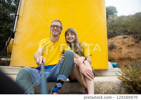 Happy Couple Taking a Selfie in a Rural Outdoor Setting with Cheerful Yellow Background 128380970