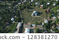 Aerial view of the church and graveyard in the village. Rustic wooden church in the center of the countryside. Rows of burials are located around the temple. 128381270