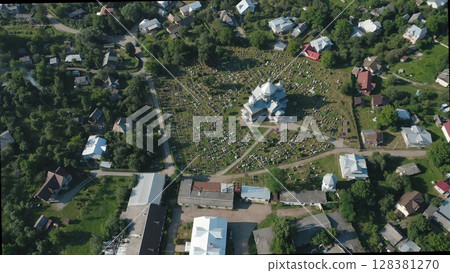 Aerial view of the church and graveyard in the village. Rustic wooden church in the center of the countryside. Rows of burials are located around the temple. Aerial view of the church and graveyard in the village. Rustic wooden church in the center of the countryside. Rows of burials are located around the temple. 128381270