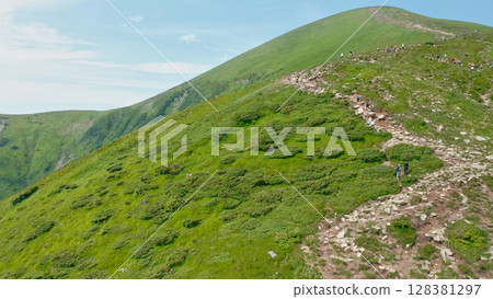 Aerial view of young tourists walking along a mountain trail with backpacks to the top of the mountain. Hiking, climbing, traveling, trekking, backpacking. Aerial view of young tourists walking along a mountain trail with backpacks to the top of the mountain. Hiking, climbing, traveling, trekking, backpacking. 128381297