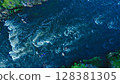Aerial view of a kayak boat rushing along a turbulent river between stone rocks at high speed. Athletes trying to steer the boat in the right direction. 128381305