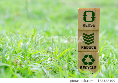 Wooden cube stack with text that reads recycle, reuse and reduce icons on green grass. Environmental concept 128382309