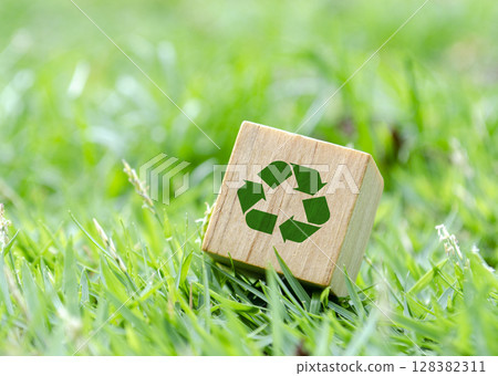 Wooden cube with recycle icon lying flat on grass. Recycling visual concept Wooden cube with recycle icon lying flat on grass. Recycling visual concept 128382311