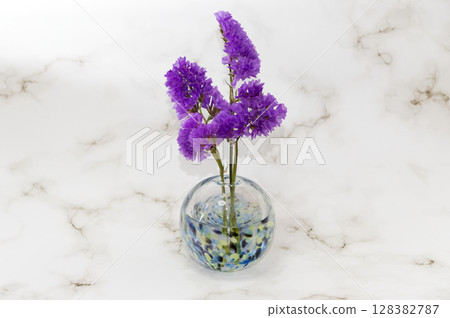 紫色補血草花,插在中央的冷色玻璃花瓶中 紫色補血草花,插在中央的冷色玻璃花瓶中 128382787