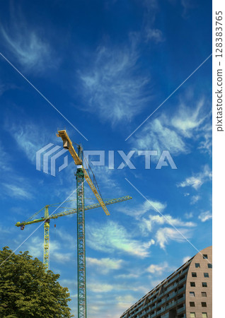 A bright construction cranes , symbolizing urban development, innovation and modern architecture. 128383765