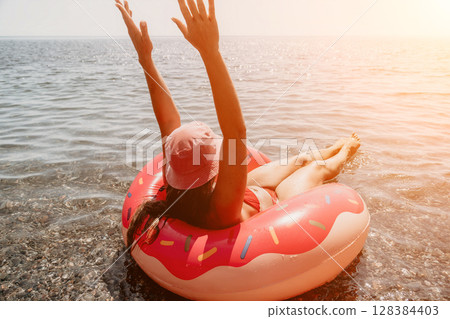Woman, Beach, Inflatable, Smiling woman floats on an inflatable ring in the ocean on a sunny day. 128384403