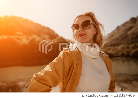 Woman in Yellow Jacket Looks Over a Mountain Landscape 128384409