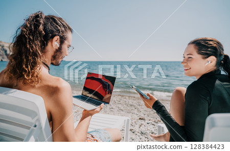Beach Laptop Couple Work Vacation - Two people working on laptops while sitting on beach chairs. Beach Laptop Couple Work Vacation - Two people working on laptops while sitting on beach chairs. 128384423