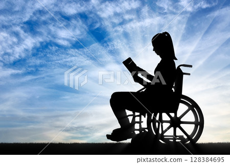 Silhouette of a disabled woman in a wheelchair reading a book Silhouette of a disabled woman in a wheelchair reading a book 128384695