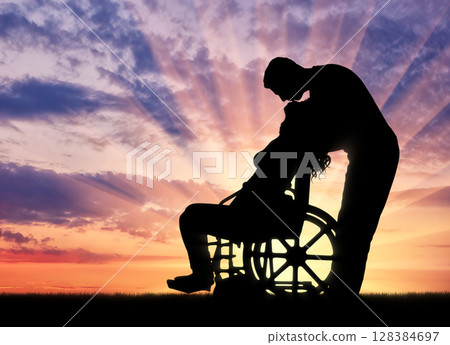 Silhouette of a man kissing a disabled woman in a wheelchair Silhouette of a man kissing a disabled woman in a wheelchair 128384697