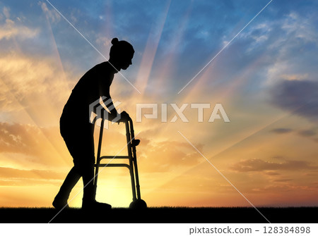 Silhouette of a disabled woman walking, using a walker 128384898