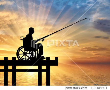 Silhouette of a disabled man in a wheelchair with a fishing rod in his hand fishing near the water 128384901