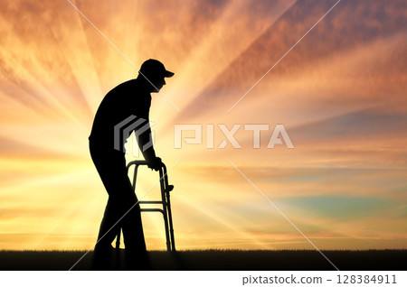 Silhouette of a disabled man walking, using a walker for the disabled 128384911