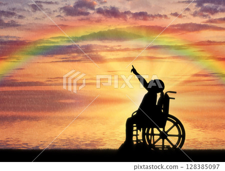 A disabled girl in a wheelchair against the background of a sea sunset with a rainbow 128385097
