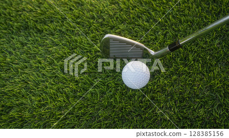 Golf clubs and balls on a green lawn in a beautiful golf course with morning sunshine. Golf clubs and balls on a green lawn in a beautiful golf course with morning sunshine. 128385156