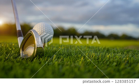 Golf clubs and balls on a green lawn in a beautiful golf course with morning sunshine. Golf clubs and balls on a green lawn in a beautiful golf course with morning sunshine. 128385157
