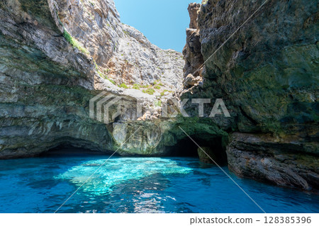 Turquoise water flows into a sea cave on Marettimo island, Italy. 128385396
