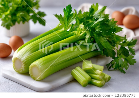 Fresh celery stalks lying on marble cutting board 128386775