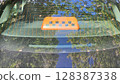 Orange taxi light sitting on rear window reflecting trees and blue sky 128387338