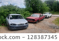 Abandoned rusty cars decaying in junkyard under cloudy sky 128387345
