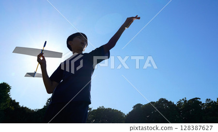 Silhouette of a boy throwing a model airplane Silhouette of a boy throwing a model airplane 128387627