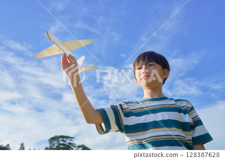A boy holding a model airplane under a blue sky A boy holding a model airplane under a blue sky 128387628