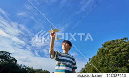 A boy holding a model airplane under a blue sky A boy holding a model airplane under a blue sky 128387630