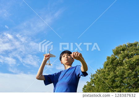 A boy flying a model airplane into the blue sky A boy flying a model airplane into the blue sky 128387632