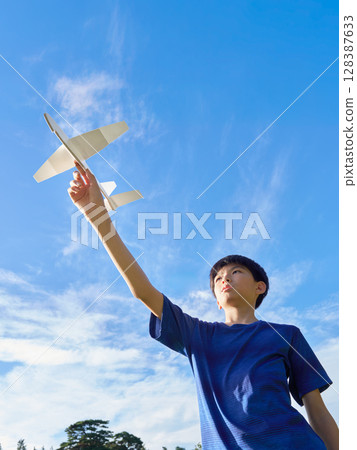 A boy flying a model airplane into the blue sky A boy flying a model airplane into the blue sky 128387633