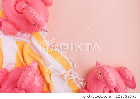 Beach essentials including an inflatable flamingos and towel on a light background. 128388553
