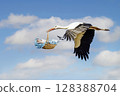 Stork carrying baby in beak flying through blue sky with clouds 128388704