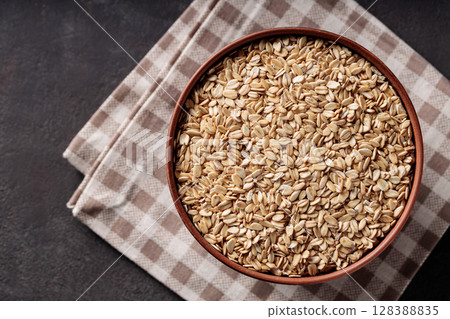 Rolled Oats in Ceramic Bowl on Brown Checkered Napkin Top View 128388835