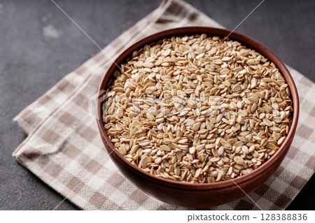 Rolled Oats in Ceramic Bowl on Brown Checkered Napkin Top View 128388836