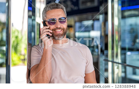 Casual businessman talking on phone outdoor. Businessman using phone. Man phone conversation. Hispanic business man with smartphone. Business communication. Man reply phone call. Copy space Casual businessman talking on phone outdoor. Businessman using phone. Man phone conversation. Hispanic business man with smartphone. Business communication. Man reply phone call. Copy space 128388948