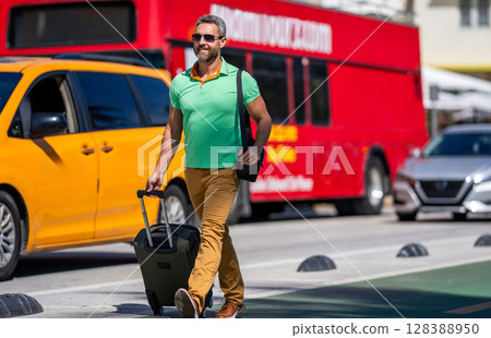 Tourist with suitcase in tropical city. Man 40s tourist on summer vacation. Traveler trip luggage. Summer tour. Traveler enjoy summer trip. Hispanic tourist traveler walking on street, advertisement Tourist with suitcase in tropical city. Man 40s tourist on summer vacation. Traveler trip luggage. Summer tour. Traveler enjoy summer trip. Hispanic tourist traveler walking on street, advertisement 128388950