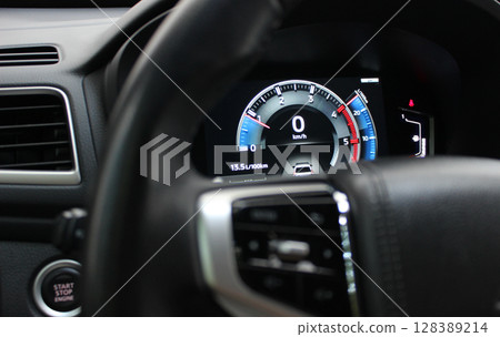 Digital tachometer with colored backlight on the central panel of a modern car 128389214