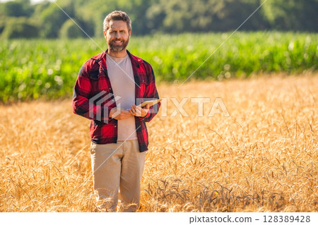 Man agronomist farmer. Crop protection. Agriculture farm. Farm man at wheat field. Crop harvest and farming. Farmer in field. Hispanic man farmer check agriculture field harvest. Lush crop growth Man agronomist farmer. Crop protection. Agriculture farm. Farm man at wheat field. Crop harvest and farming. Farmer in field. Hispanic man farmer check agriculture field harvest. Lush crop growth 128389428