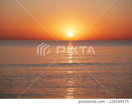 Vivid sunset over the sea with a glowing sun and golden reflection on the calm water. Peaceful and captivating atmosphere. Nature background, relaxation concept, travel theme and inspirational visual Vivid sunset over the sea with a glowing sun and golden reflection on the calm water. Peaceful and captivating atmosphere. Nature background, relaxation concept, travel theme and inspirational visual 128389575