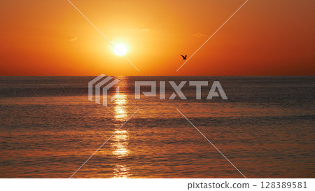 Vivid sunset over the sea with a glowing sun and golden reflection on the calm water. Peaceful and captivating atmosphere. Nature background, relaxation concept, travel theme and inspirational visual Vivid sunset over the sea with a glowing sun and golden reflection on the calm water. Peaceful and captivating atmosphere. Nature background, relaxation concept, travel theme and inspirational visual 128389581
