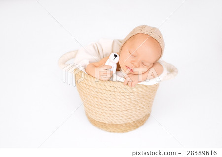 Photo of a newborn baby in a basket with knitted toy dog in hand. Photo of a newborn baby in a basket with knitted toy dog in hand. 128389616