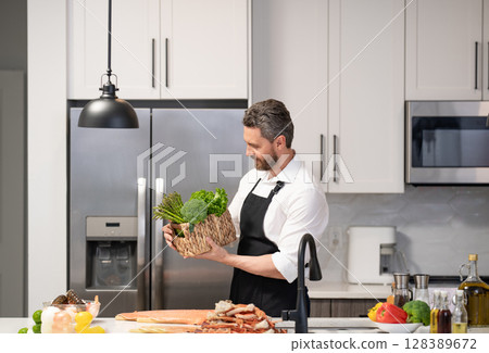 Healthy food diet. Man cook tasty meal. Home menu with seafood food. Man cook cooking at kitchen. Hispanic man standing in kitchen preparing sea food. Man cook tasty crab leg. Seafood recipes 128389672
