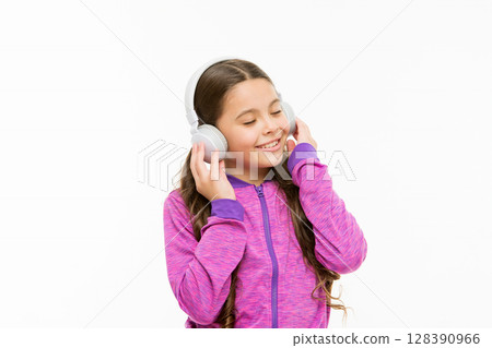 Tuning into a wave of real sound. Cute kid listening to sound track isolated on white. Active child enjoy electronic sound playing in earphones. Athletic little girl relaxing with melodious sound 128390966