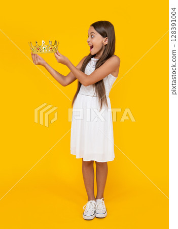 shocked teen girl in crown on yellow background shocked teen girl in crown on yellow background 128391004