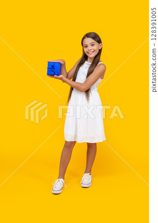 happy teen girl hold present box on yellow background happy teen girl hold present box on yellow background 128391005
