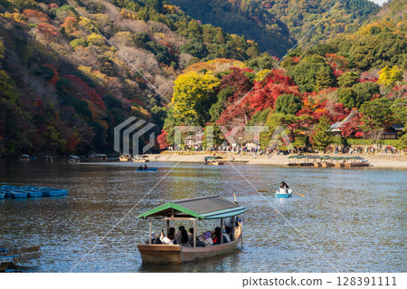 遊客們乘坐屋形船，在蘭峽的秋葉中沿著大井川航行 128391111