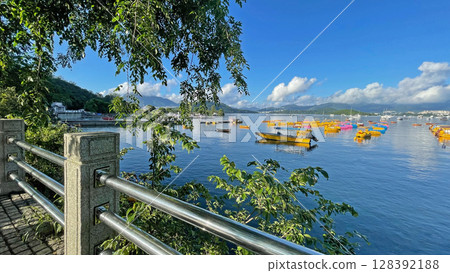 Fishing, recreational boats on bay, natural background with trees, clouds, blue sky and mountains 128392188