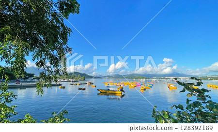 Fishing, recreational boats on bay, natural background with trees, clouds, blue sky and mountains 128392189